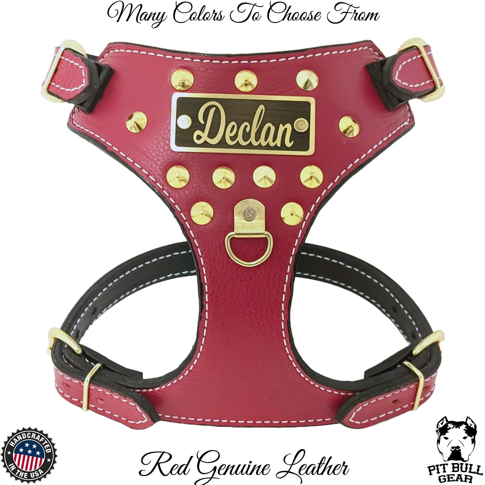 A red full-grain leather dog harness with cone studs and a custom engraved name plate reading 'Declan'. It features adjustable straps, a heavy-duty buckle, and a welded D-ring for leash attachment.